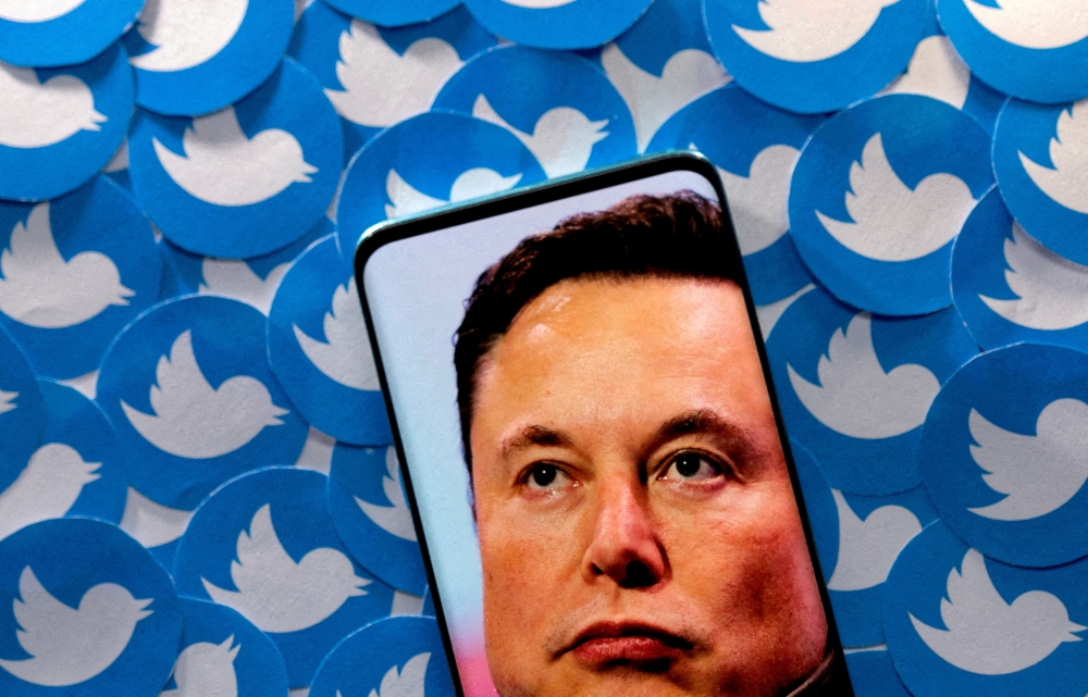 File Photo: An image of Elon Musk is seen on smartphone placed on printed Twitter logos in this picture illustration taken April 28, 2022. (REUTERS/Dado Ruvic)