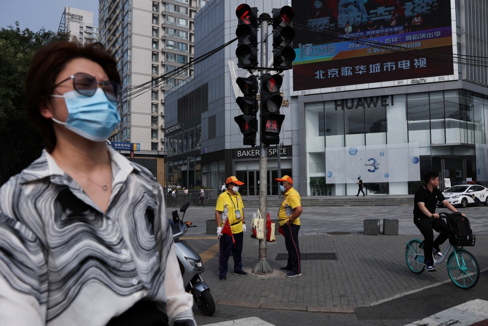 People wait at an intersection on a street during morning rush hour, in Beijing's Central Business District, China, August 2, 2022. (REUTERS/Tingshu Wang)