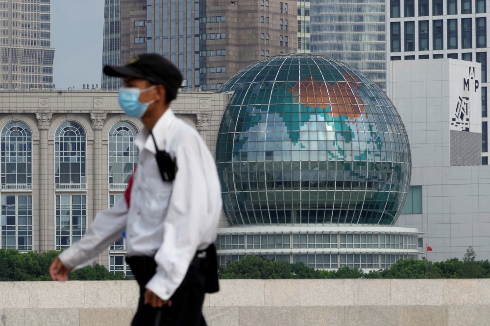 A security guard wearing a face mask following the coronavirus disease (Covid-19) outbreak walks past a globe in Shanghai, China, August 2, 2022. (REUTERS/Aly Song)