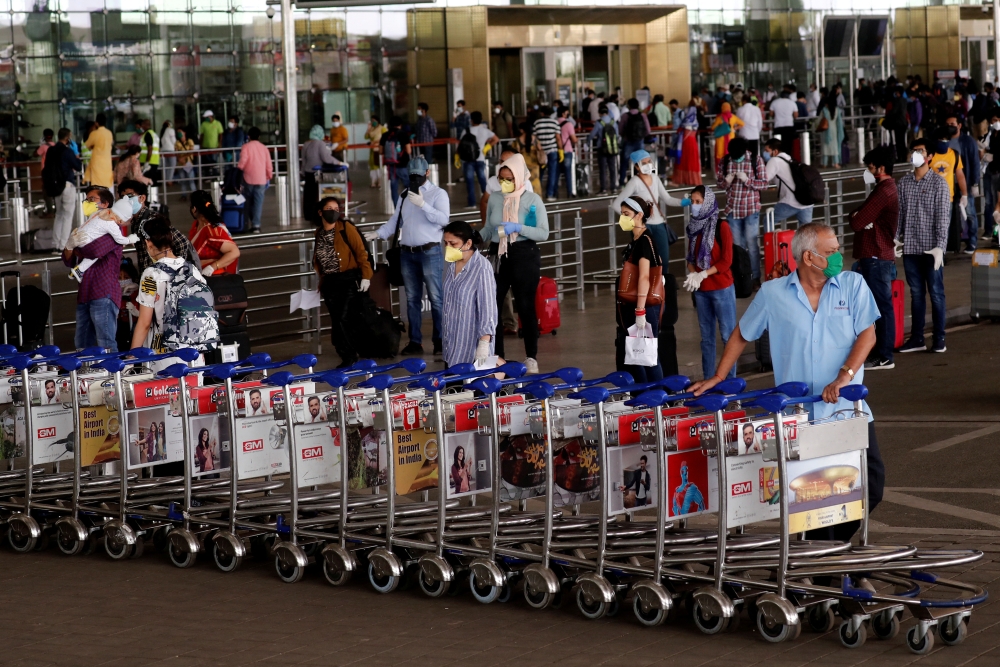 An airport staff member pushes trollies at the entrance of Chhatrapati Shivaji International Airport, after the government allowed domestic flight services to resume, during an extended nationwide lockdown to slow the spread of the coronavirus disease (COVID-19), in Mumbai, India, May 25, 2020. REUTERS/Francis Mascarenhas/File Photo