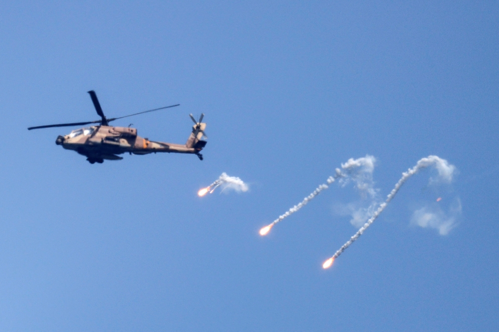 An Israeli Air Force Apache helicopter fires flares in the sky above the Israel-Gaza border on August 7, 2022. (REUTERS/Amir Cohen)