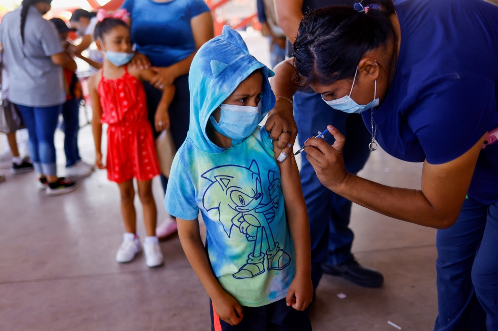 A child receives a dose of the Pfizer-BioNTech coronavirus disease (Covid-19) pediatric vaccine during a mass vaccination program for children ages 6 to 7 in Ciudad Juarez, Mexico, August 9, 2022. (REUTERS/Jose Luis Gonzalez)