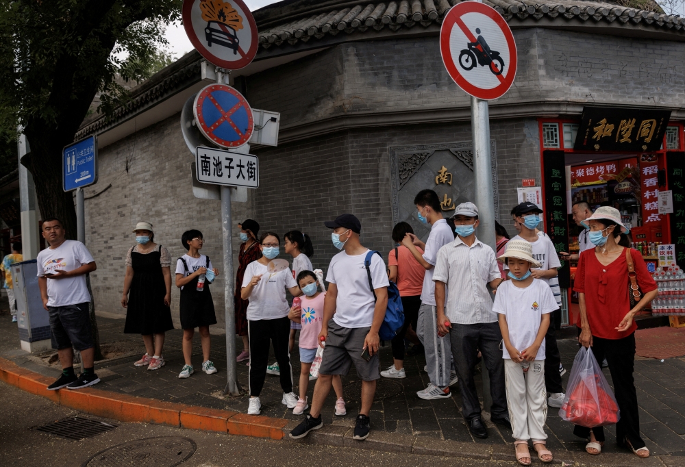 People wear face masks as they stand in a street following a coronavirus disease (COVID-19) outbreak, in Beijing, China, August 3, 2022. Reuters/Thomas Peter/File Photo