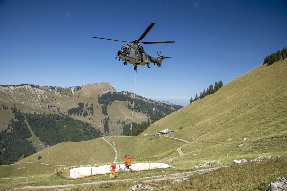 A Swiss Air Force Super Puma helicopter delivers water for cows in the Tissiniva mountain pasture due to an ongoing drought in Charmey, Switzerland, August 10, 2022. REUTERS/Denis Balibouse


