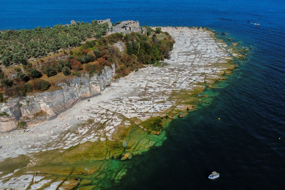 Underwater rocks emerge from the water of Lake Garda after northern Italy experienced the worst drought in 70 years in Sirmione, Italy, August 16, 2022. REUTERS/Flavio Lo Scalzo/Files

