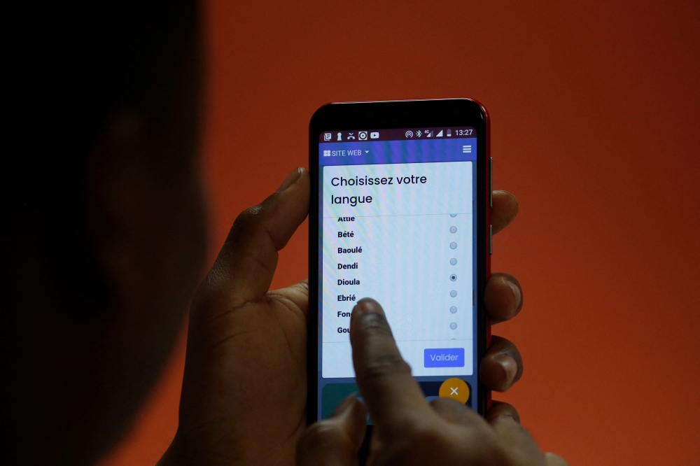 A customer holds the Open G smartphone, which can speak local Ivorian languages, at a shop in Abidjan, Ivory Coast July 25, 2022. REUTERS/Luc Gnago