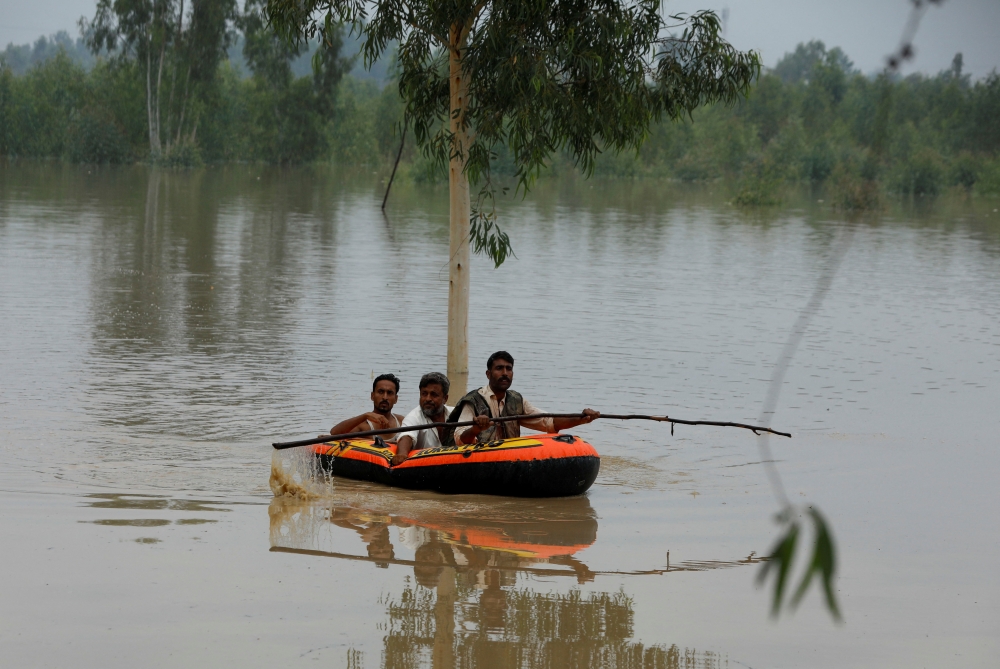 A volunteer rows an inflatable boat as he evacuates flood victims, following rains and floods during the monsoon season in Charsadda, Pakistan August 27, 2022. REUTERS/Fayaz Aziz