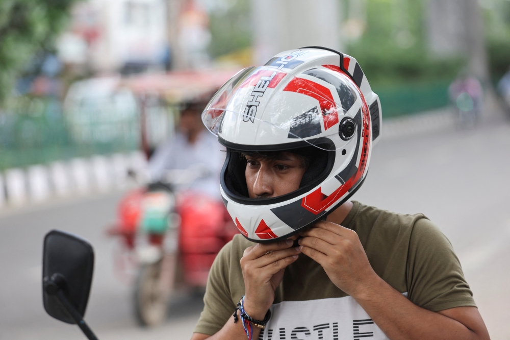 An employee of Shellios Technolabs, that manufactures motorcycle helmet claimed to be fitted with filters and a fan at the back of the helmet, puts on the helmet, near their assembling factory unit in an industrial area, in New Delhi, India, August 23, 2022. REUTERS/Anushree Fadnavis
