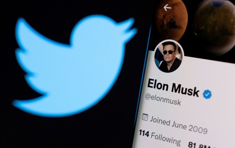 Elon Musk's twitter account is seen on a smartphone in front of the Twitter logo in this photo illustration taken on April 15, 2022. REUTERS/Dado Ruvic/Illustration/File Photo
