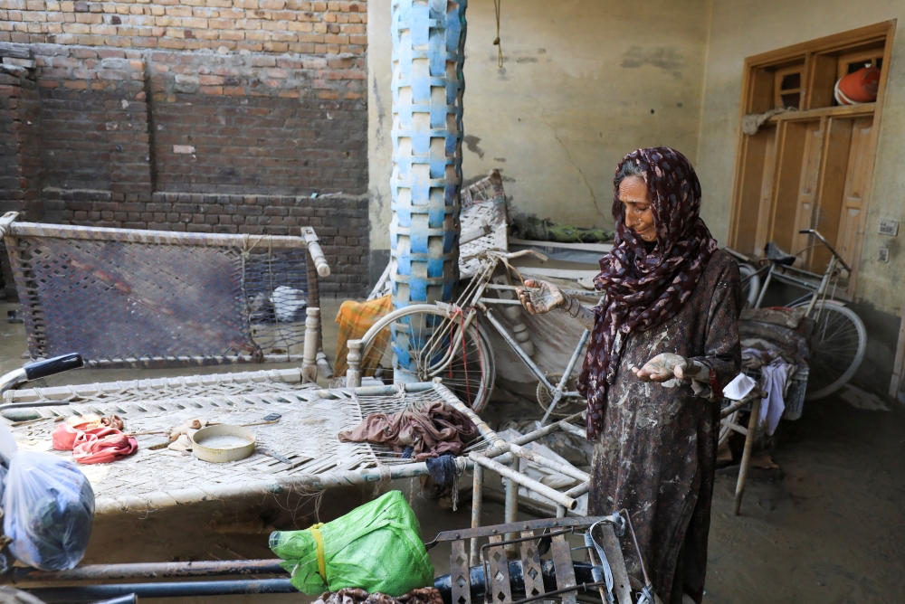A woman reacts as she goes through her belongings, following rains and floods during the monsoon season in Nowshera, Pakistan, on September 1, 2022. REUTERS/Fayaz Aziz