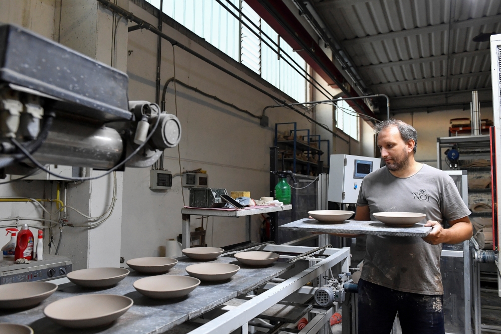 An employee works at a ceramics factory where the workers start their shifts before dawn to optimise sunlight and save energy, in Citta di Castello, Italy, August 30, 2022. REUTERS/Jennifer Lorenzini