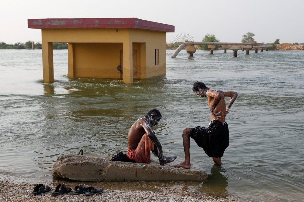 Men who became displaced take a bath amid flood water, following rains and floods during the monsoon season in Sehwan, Pakistan, on September 13, 2022. REUTERS/Akhtar Soomro/File Photo