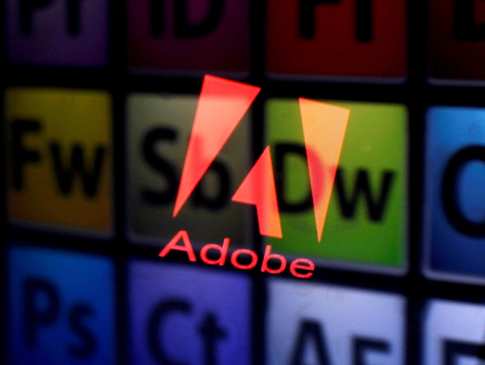 An Adobe logo and Adobe products are seen reflected on a monitor display and an iPad screen, in this picture illustration July 8, 2013. File Photo / Reuters