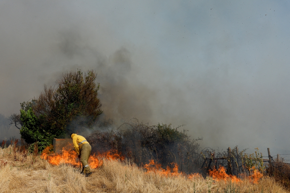 A firefighter works to extinguish a wildfire amid Spain's second heatwave of the year, in Faramontanos de Tabara, Spain, July 19, 2022. REUTERS/Borja Suarez/File Photo