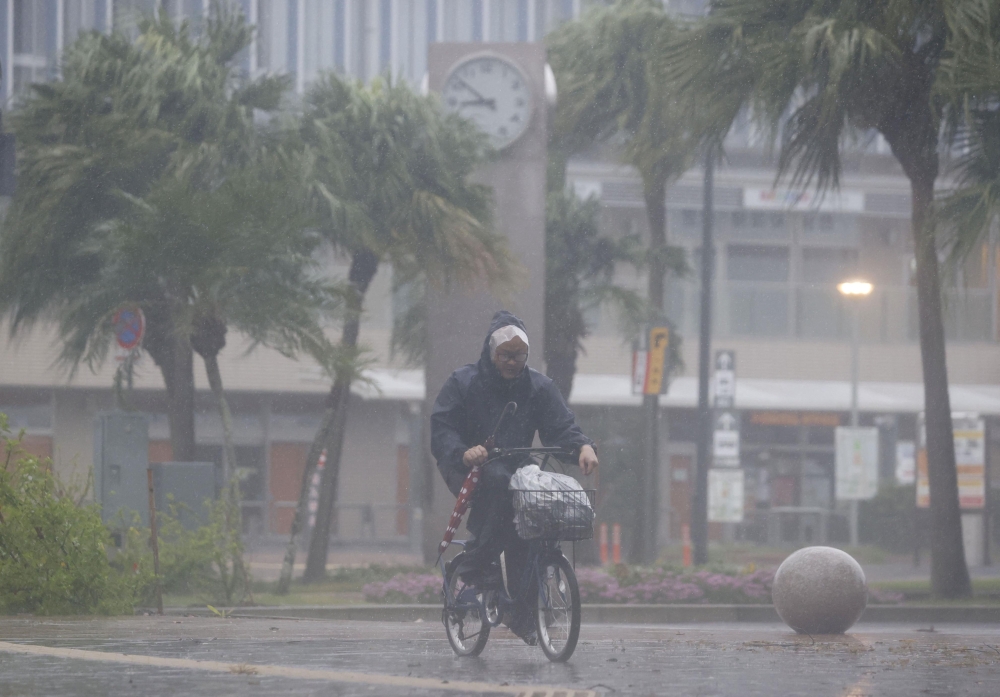 A man on a bicycle rides past in the heavy rain and wind caused by Typhoon Nanmadol in Miyazaki on Japan's southernmost main island of Kyushu September 18, 2022, in this photo taken by Kyodo. Mandatory credit Kyodo via REUTERS