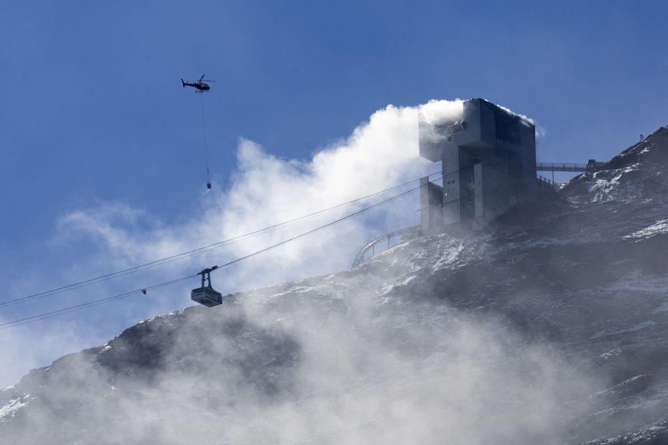 An helicopter carries water to stop an ongoing fire at the restaurant Botta at the Glacier 3000 resort in Les Diablerets, Switzerland, September 19, 2022. REUTERS/Denis Balibouse


