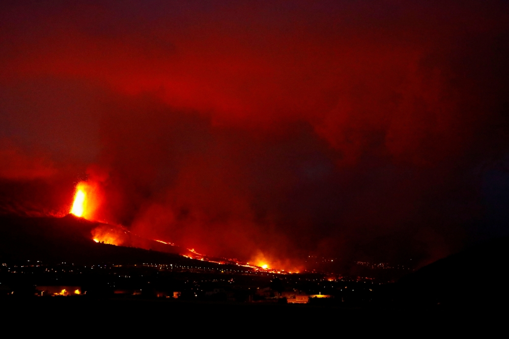 Lava flows behind houses following the eruption of a volcano in the Cumbre Vieja national park, in this picture taken from Tazacorte, on the Canary Island of La Palma, Spain September 20, 2021. REUTERS/Borja Suarez

