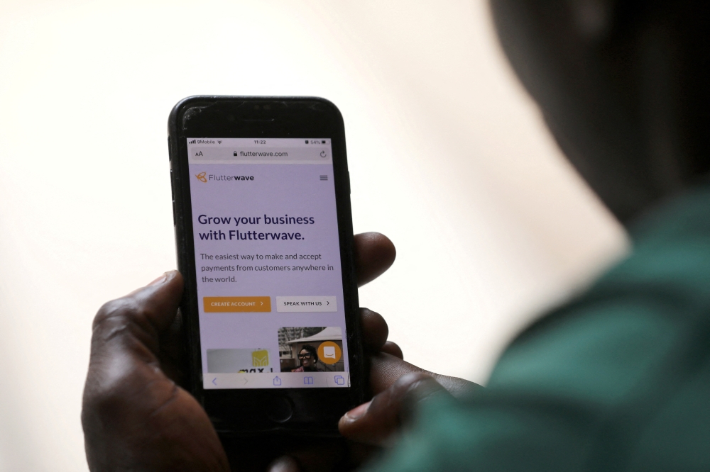 A man poses as he displays the Flutterwave homepage on a mobile phone screen in Abuja, Nigeria January 21, 2020. REUTERS/Afolabi Sotunde/File Photo