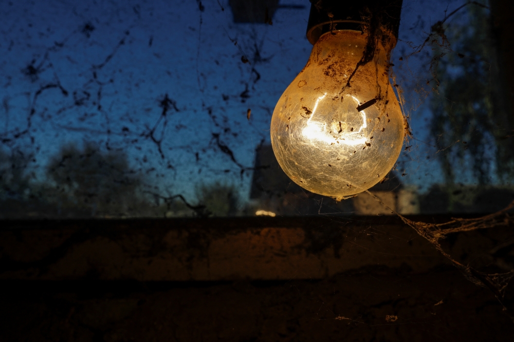 An incandescent light bulb is covered in spider webs inside a stable in Vasilati, Calarasi county, 30 kilometers from Bucharest, Romania, October 17, 2022. Inquam Photos/Octav Ganea via REUTERS