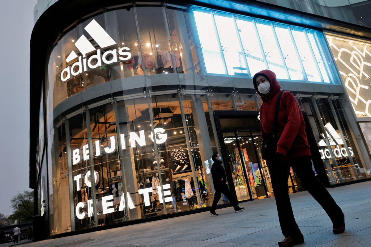 People walk past an Adidas store in a shopping district following an outbreak of the coronavirus disease (COVID-19) in Beijing, China, April 5, 2021. (REUTERS/Thomas Peter)