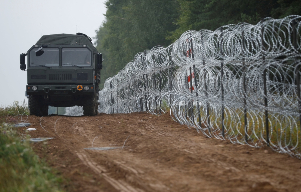  A view of a vehicle next to a fence built by Polish soldiers on the border between Poland and Belarus near the village of Nomiki, Poland, on August 26, 2021.   File Photo / Reuters
