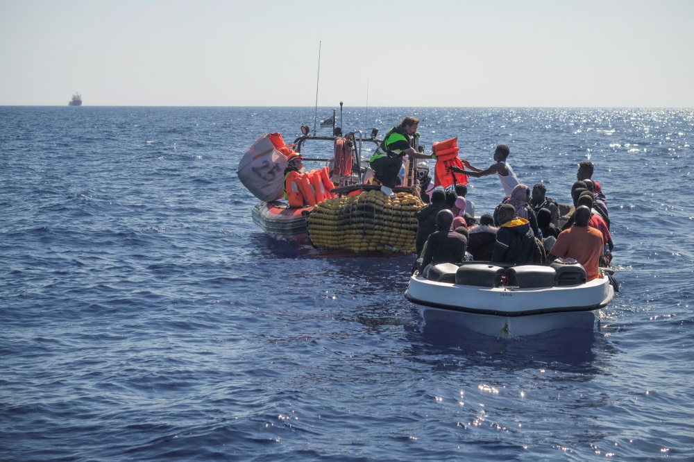 Crew members of NGO rescue ship 'Ocean Viking' give lifejackets to migrants on an overcrowded boat in the Mediterranean Sea, on October 25, 2022. Camille Martin Juan/Sos Mediterranee/Handout via REUTERS 