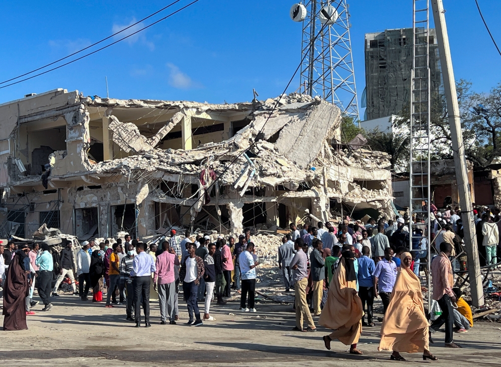 Civilians gather near the ruins of a building at the scene of an explosion along K5 street in Mogadishu, Somalia, October 30, 2022. (REUTERS/Abdirahman Hussein)