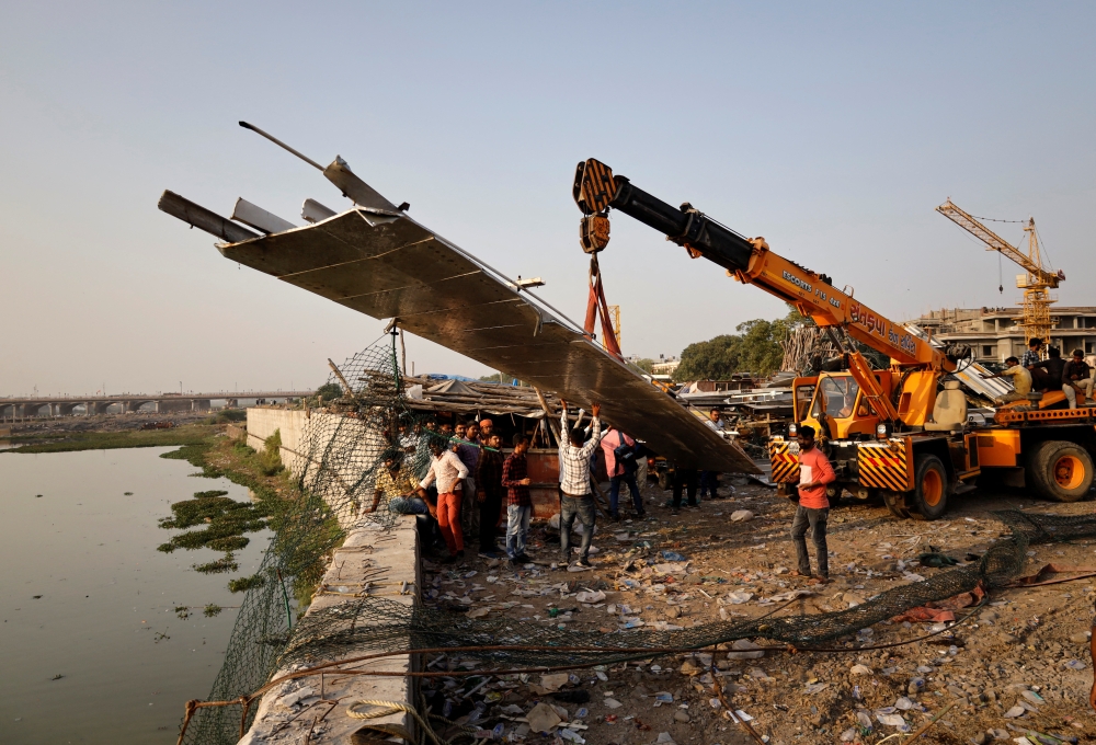 People remove debris after a suspension bridge collapsed in Morbi town in the western state of Gujarat, India, on October 31, 2022. REUTERS/Stringer 