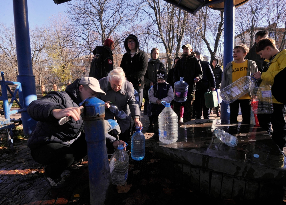 Kyiv residents fill plastic containers and bottles at a water pump in one of the parks in the Ukrainian capital Kyiv on October 31, 2022. - Ukraine suffered sweeping blackouts and water supplies were cut for 80 percent of Kyiv residents on October 31, 2022, after what Ukrainian officials called another 