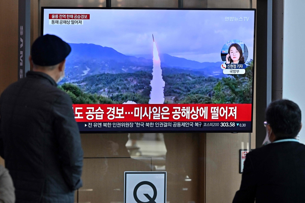 People watch a television screen showing a news broadcast with file footage of a North Korean missile test, at a railway station in Seoul on November 2, 2022. Photo by JUNG YEON-JE / AFP
