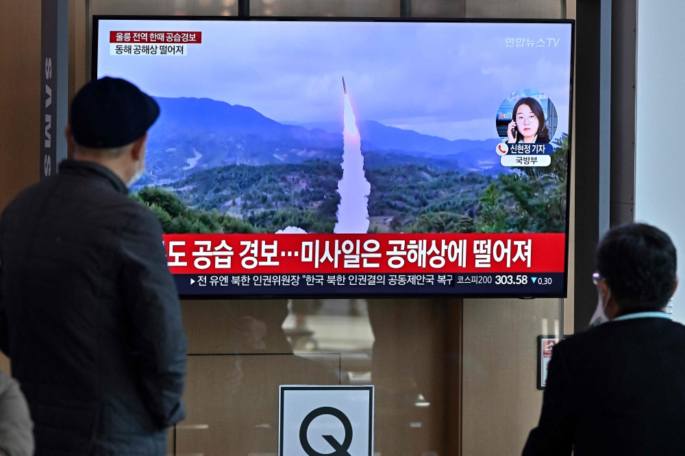 People watch a television screen showing a news broadcast with file footage of a North Korean missile test, at a railway station in Seoul on November 2, 2022. Photo by JUNG YEON-JE / AFP