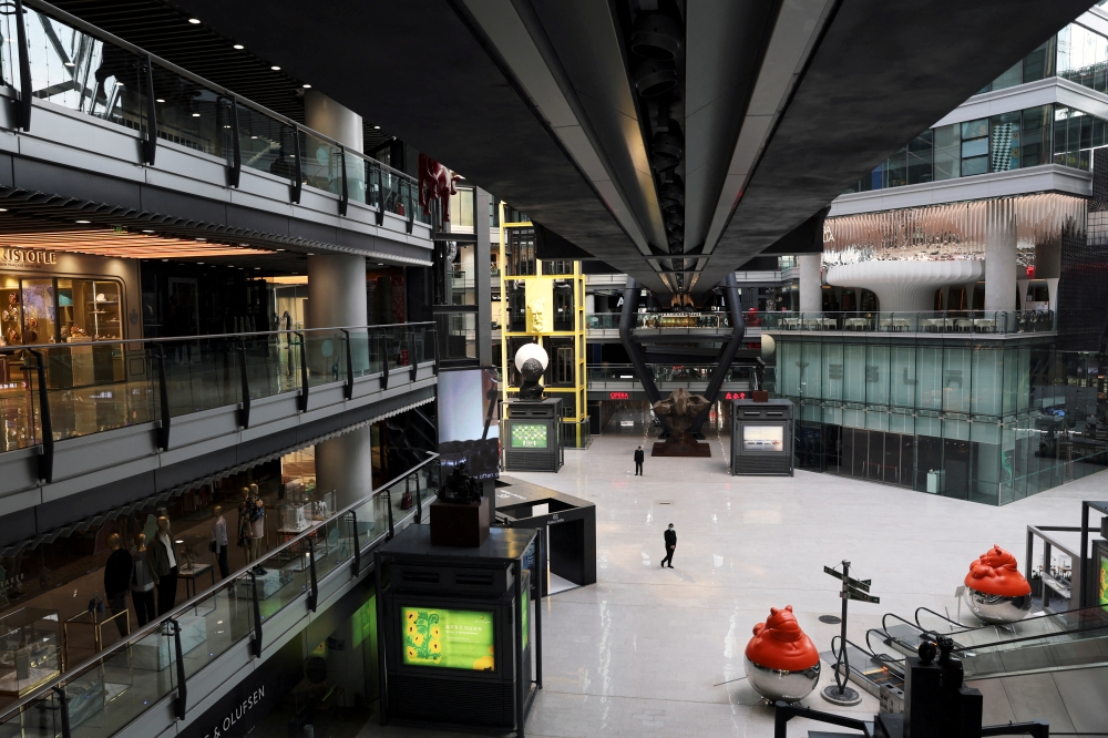People stand near a Tesla's showroom inside the Parkview Green shopping mall where most shops are closed, amid the coronavirus disease (COVID-19) outbreak in Beijing, China, on May 9, 2022.  File Photo / Reuters