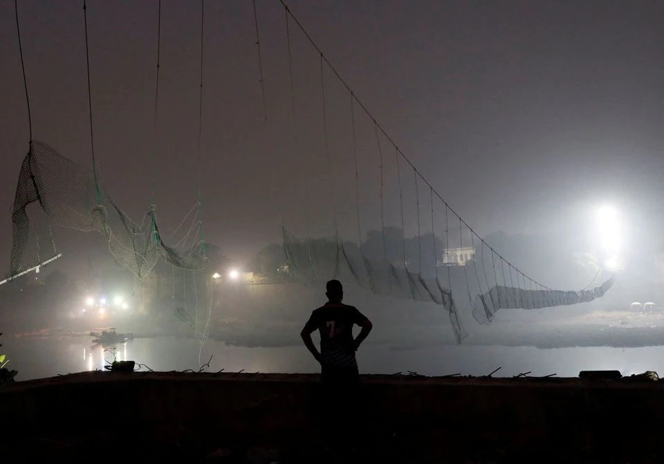 A security personnel stands near a damaged suspension bridge after it collapsed on Sunday, in Morbi town in the western state of Gujarat, India, November 1, 2022. REUTERS/Stringer/File Photo
