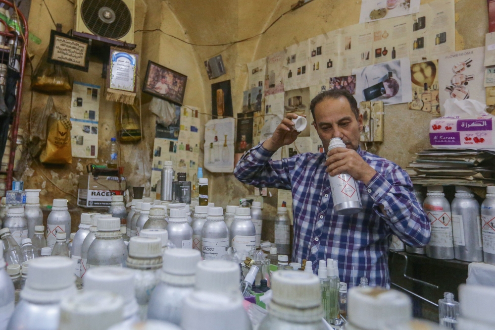 Syrian perfumer Mohammad al-Masri works at his shop in a historic souq of Damascus's old city on October 31, 2022. (AFP/Louai Beshara)