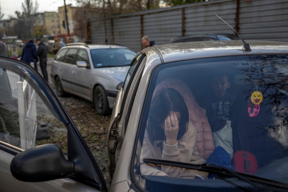 A Ukranian woman sits in a car with her family after they managed to flee from the Russian occupied territory of Kherson, on November 5, 2022, in Zaporizhzhia. (Photo by BULENT KILIC / AFP)