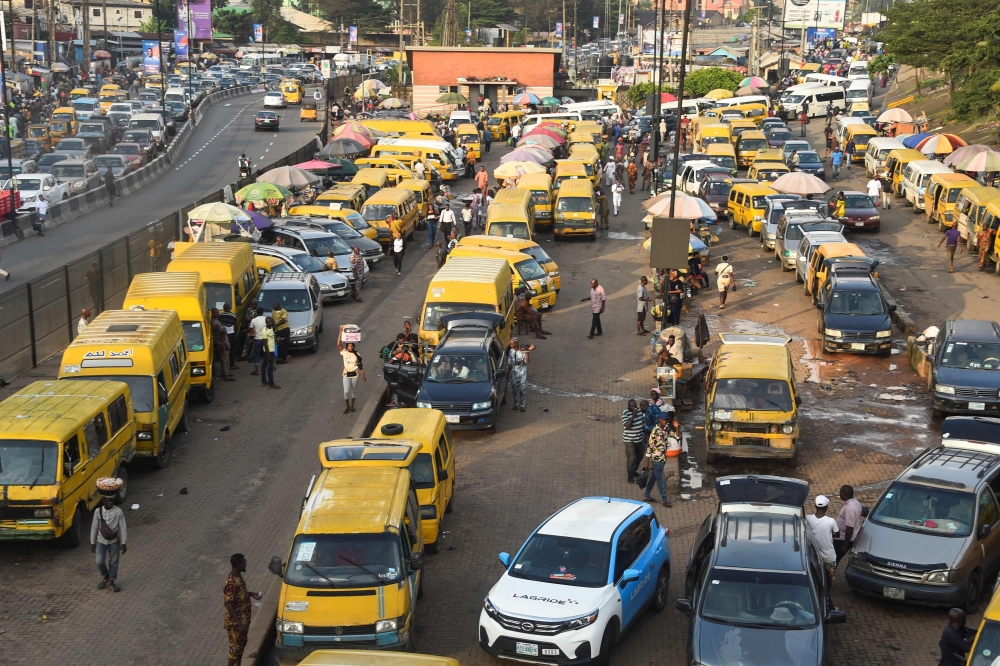 Vehicles drive in chaotic traffic gridlock past yellow painted mini buses, popularly called Danfo, parked at Ojodu-Berger bus station in Lagos, Nigeria's commercial capital, on October 19, 2022. (Photo by PIUS UTOMI EKPEI / AFP)