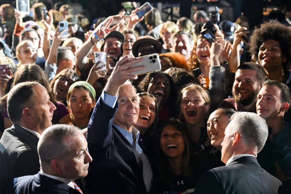 US President Joe Biden (C) poses for a selfie with supporters during a rally for Democratic candidates, including New York Governor Kathy Hochul, at Sarah Lawrence College in Bronxville, New York, on November 6, 2022. (Photo by SAUL LOEB / AFP)
 