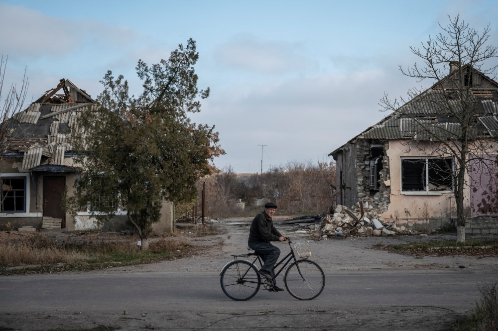 A local resident rides a bike near destroyed houses, amid Russia's attack on Ukraine, in the village of Arkhanhelske, Kherson region, Ukraine, November 8, 2022. (REUTERS/Viacheslav Ratynskyi)