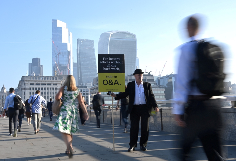 Workers pass by a sales person as they walk towards the City of London financial district as they cross London Bridge during the morning rush hour in London, Britain, on September 8, 2021. File photo / Reuters
