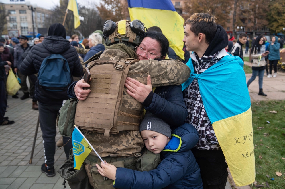 Local residents hug a Ukrainian soldier as they celebrate the liberation of Kherson, on November 13, 2022. (AFP)