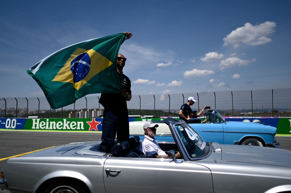 Mercedes' British driver Lewis Hamilton waves a Brazilian national flag during the drivers' parade ahead of the Formula One Brazil Grand Prix at Jose Carlos Pace racetrack, also known as Interlagos, in Sao Paulo, on November 13, 2022. (Photo by MAURO PIMENTEL / AFP)