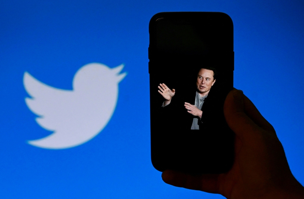(FILES) In this file photo taken on October 4, 2022, a phone screen displays a photo of Elon Musk with the Twitter logo shown in the background, in Washington, DC. AFP