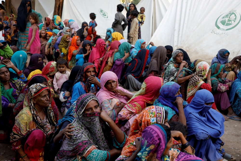 File photo: Women displaced because of the floods wait to receive food handouts while taking refuge in a camp, in Sehwan, Pakistan, September 30, 2022. (Reuters/Akhtar Soomro)