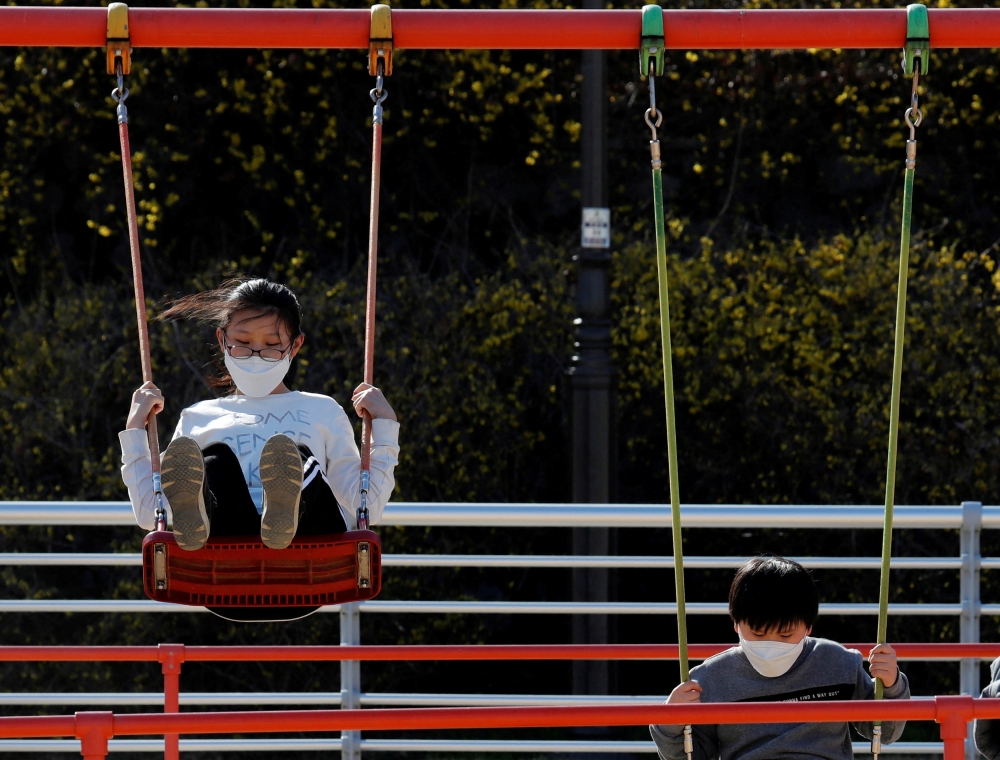 Children wearing masks following the rise in confirmed cases of coronavirus disease (COVID-19), play on the swings at a park in Daegu, South Korea, March 14, 2020. REUTERS/Kim Kyung-Hoon/File Photo