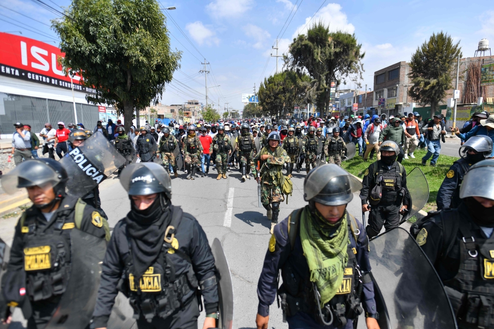 Members of the police escort supporters of former President Pedro Castillo while they march to the center of the city of Arequipa, Peru, demanding the closure of Congress and the release of Castillo, on December 14, 2022.  (Photo by Diego Ramos / AFP)