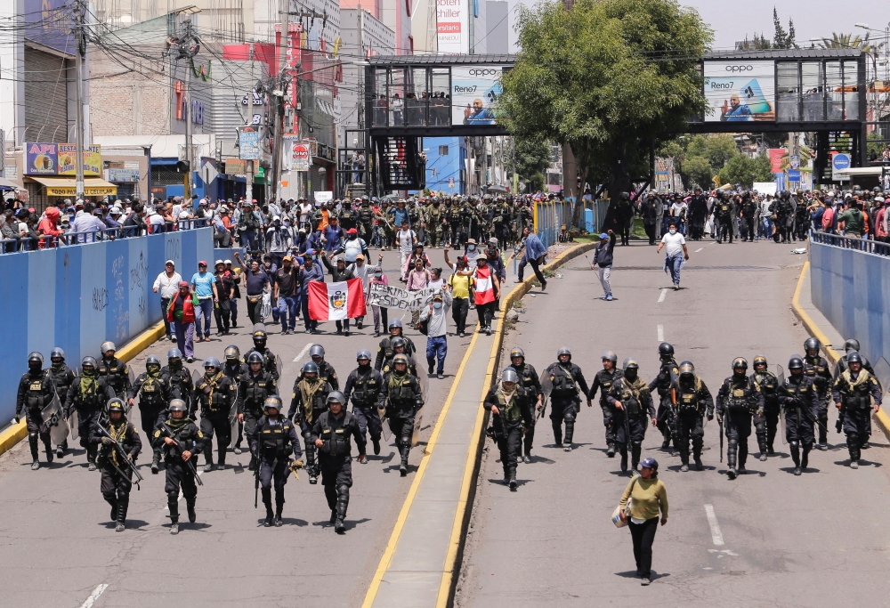 Police officers walk beside protesters taking part in a march demanding the dissolution of the Congress and to hold democratic elections rather than recognising Dina Boluarte as Peru's President, after the ouster of Peruvian leader Pedro Castillo in Arequipa, Peru, December 14, 2022. (REUTERS/Oswald Charca)