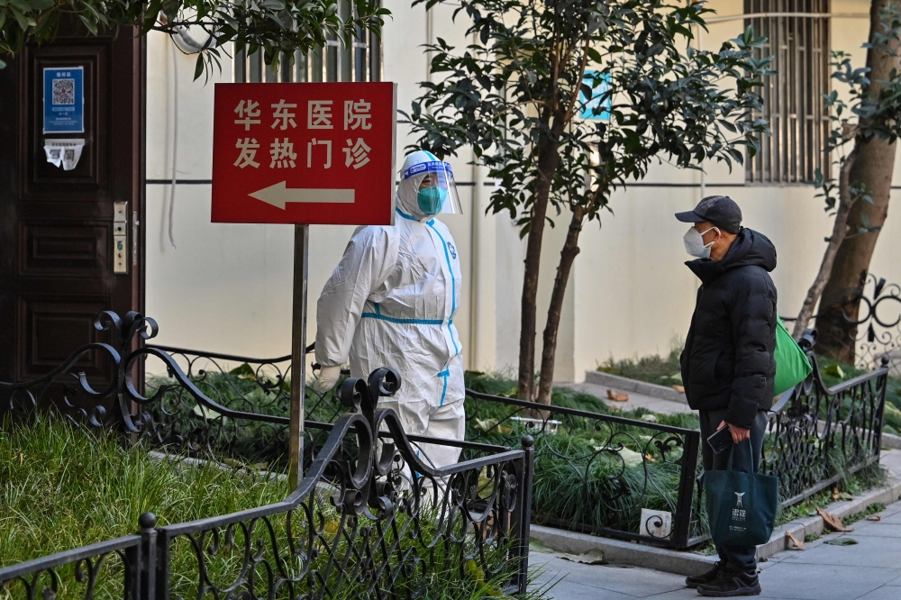 A health worker wearing protective equipment (PPE) stands at the entrance of a fever clinic of a hospital in Shanghai on December 18, 2022. (Photo by HECTOR RETAMAL / AFP)