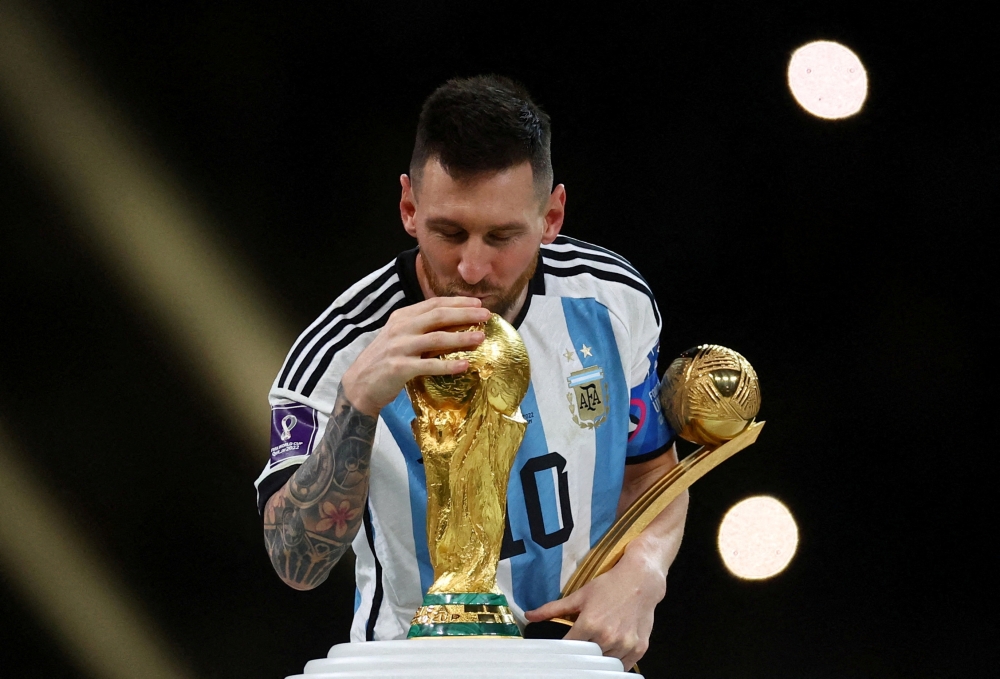 Argentina's Lionel Messi kisses the World Cup trophy after receiving the Golden Ball award as he celebrates after winning the FIFA World Cup in Qatar on December 18, 2022. (REUTERS/Kai Pfaffenbach)
