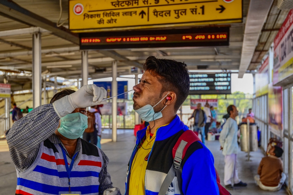 A health worker collects a swab sample for Covid-19 screening from a passenger arriving at Prayagraj junction on December 23, 2022. (Photo by Sanjay Kanojia / AFP)