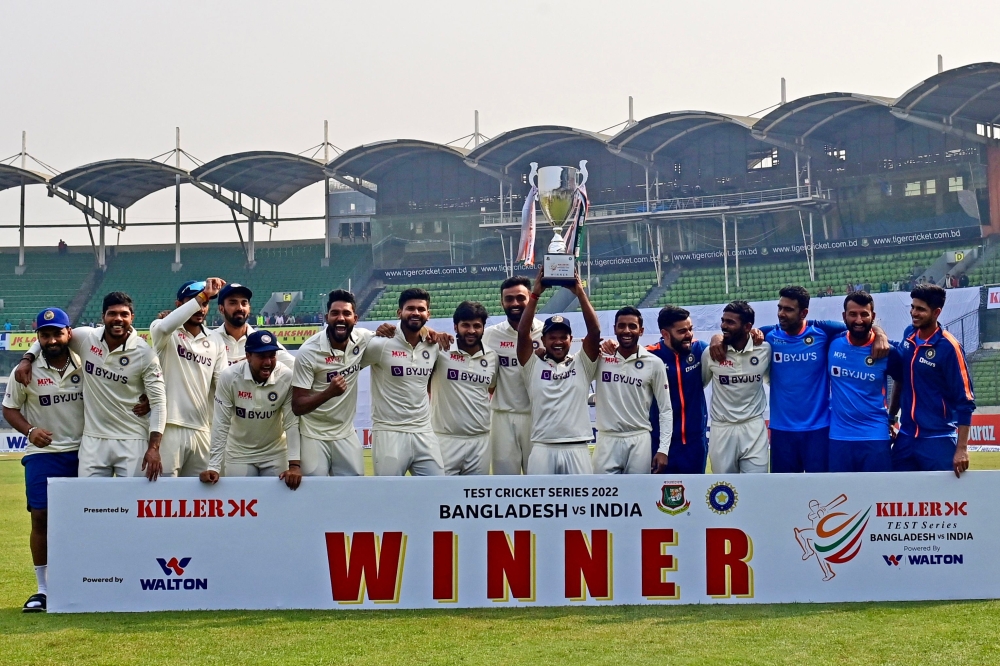India's cricketers pose for a photo as they hold the tournament trophy after winning on the fourth day of the second cricket Test match between Bangladesh and India at the Sher-e-Bangla National Cricket Stadium in Dhaka on December 25, 2022. (Photo by Munir uz Zaman / AFP)